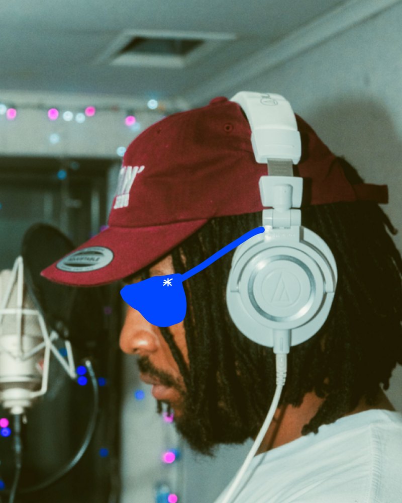 Denzel Johnson in a red cap and headphones at a microphone, with a blue scribbled eye patch