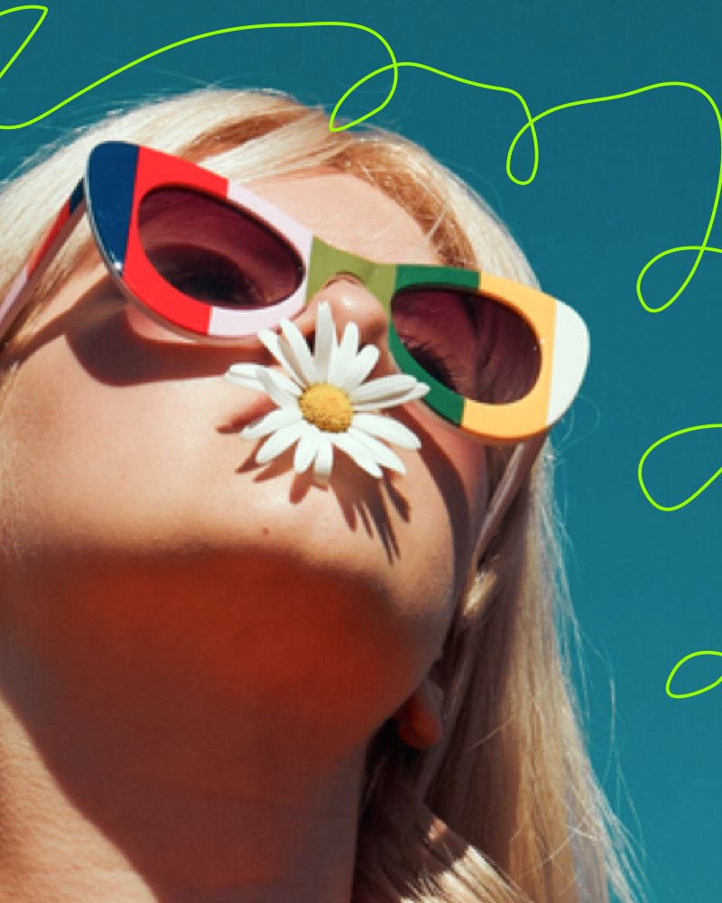 Pearl in rainbow sunglasses with a daisy in her mouth, circled by green looping scribbles