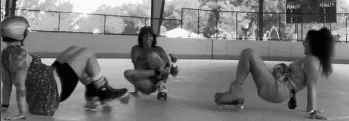 Three skaters sitting and stretching on a rink floor